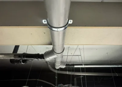 Afvoerleiding gemonteerd aan plafond in winkelpand